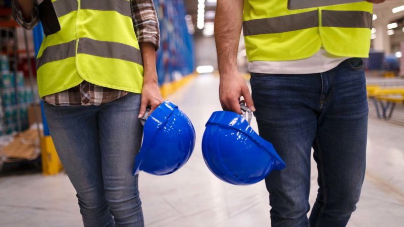 ¿Qué son las placas de fibrosilicato y cómo ayudan en la prevención de incendios? 10 two unrecognizable workers in reflective suit walking through warehouse and holding blue protective hardhats