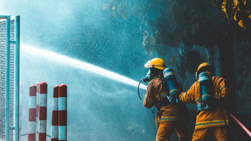 ¿Por qué es importante contar con material contra incendios en un negocio industrial? 6 firefighters spray water to wildfire
