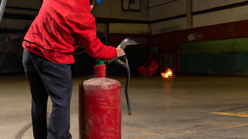 Consejos para elegir el material contra incendios adecuado en tu empresa 8 persona sujetando un extintor en una nave industrial 1